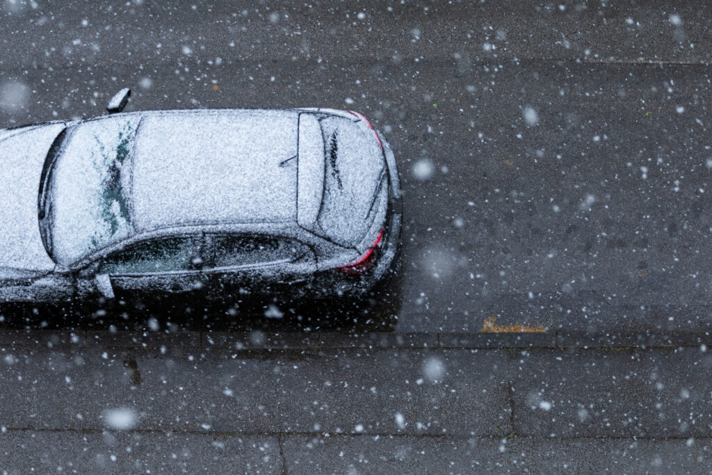 car on the road while falling snow